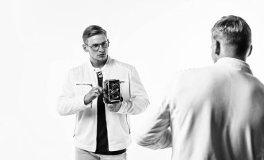 Beyaz elbiseli ikiz kardeş fotoğrafçılar birbirine benzer. Klasik fotoğraf makinesi kullanırlar, fotoğraf çekerler..