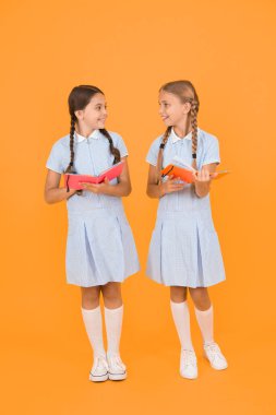 Samimi ilgi. Okul kütüphanesi. Okul için eğitim kitapları. Kitap okuyorum. Okumak ve yeniden anlatmak. Kitapları sarı arka planda tutan küçük çocuklar. Ansiklopedi veya çocuk kitapları ile küçük kızlar.