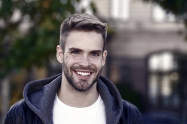 Mükemmel gülümseme. Yakışıklı bir erkek portresi. Yüz kılı ve cilt bakımı konsepti. Yakışıklı bir yüz. Yakışıklı, tıraşsız bir yüz ve şık saçlar. Beyaz adam şehir geçmişi var. Sıradan görünümlü sakallı adam..