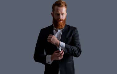 İrlandalı adam kelepçeleri ayarlıyor. Smokin giyen sakallı adam. Resmi kıyafet giymiş sakallı bir iş adamı. Yakışıklı kızıl saçlı beyefendi stüdyosu Grey 'de izole edilmiş..