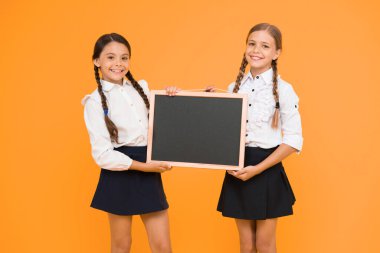 Hazırlandım. Küçük öğrenciler. Küçük kızlar sarı arka planda tahta tutuyorlar. Eğitim için siyah tahtası olan küçük okul çocukları. Küçük çocuklar ders için okul tebeşir tahtası hazırlanıyor, kopya alanı.