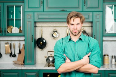 Maço ile ciddi bir yüz, sarı saçlı mavi gömlekli hazır mutfak katlanmış ellerle. Yiyecek hazırlama, kavram yemek mutfağı.