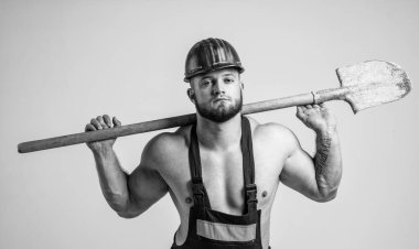 Yakışıklı adam kürekle çalışırken iş kıyafeti ve kask giyer..