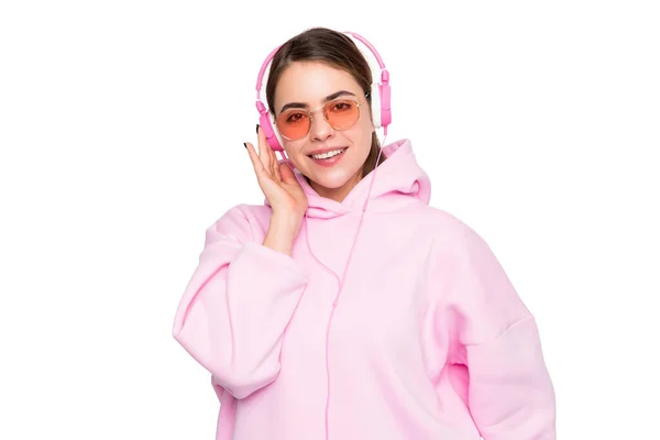 幸せな女性でピンクパーカーと眼鏡で音楽を聴いてヘッドフォンで隔離された白 — ストック写真