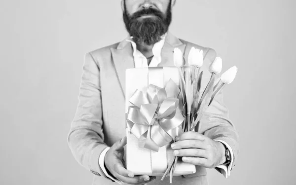 well groomed man in wedding formalwear has beard hold tulip flower and present box, valentines day.