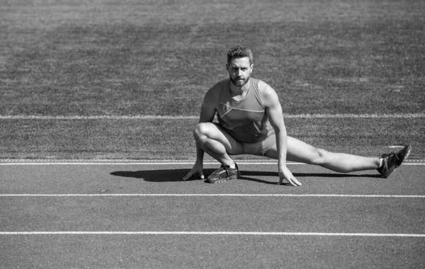 Fitness man. fitness gym outdoor. muscular athletic guy training. sport. male stretch muscles. sportsman relax. athlete train his flexibility. be flexible. man doing stretching exercise on stadium.