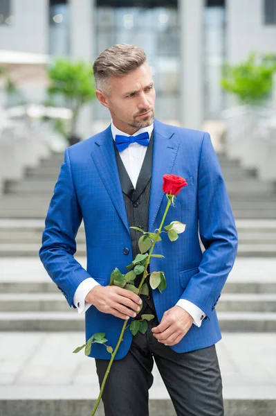 elegant man in suit at romantic occasion. man with romantic present. handsome romantic man with rose.