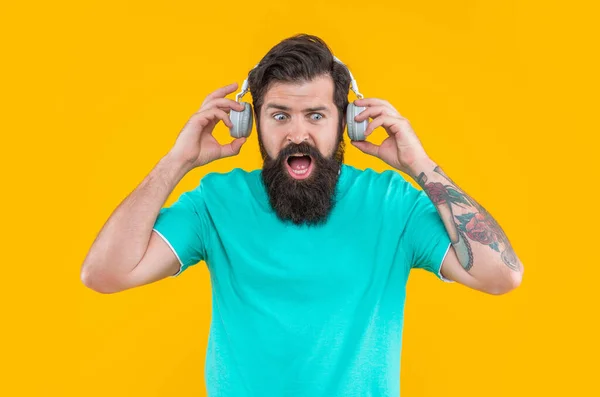 令人惊讶的是 恼怒的人在耳机里放着用黄色隔开的嘈杂的音乐 讨厌的人在耳机里听吵闹的音乐 戴耳机的男人被吵吵闹闹的音乐惹恼了 被嘈杂的音乐惹恼的人的演播室镜头 — 图库照片