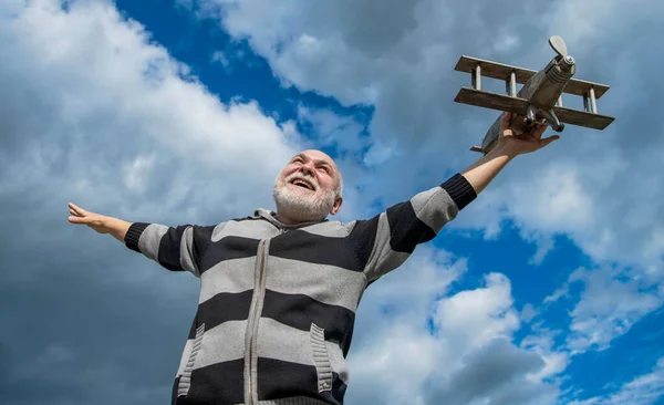 stock image freedom of senior man on sky background. senior man at retirement. senior retired man with toy plane outdoor.