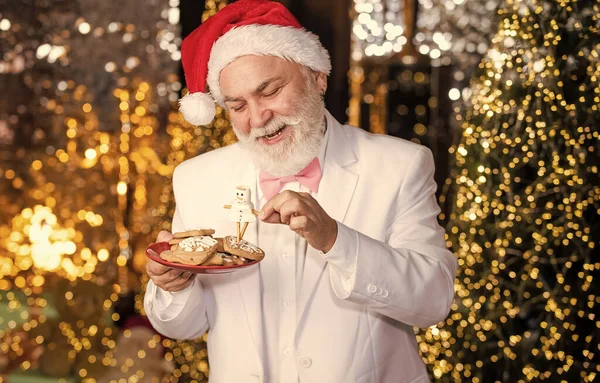 Cafe restaurant. Cooking recipe. Ginger cookies. Happy businessman hold cookies. Senior businessman in santa claus hat. Christmas sweets and treats. Christmas decor. Gingerbread concept. Dieting.