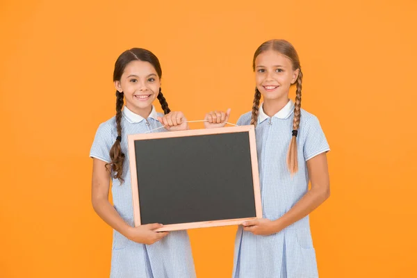 欢快的朋友在复古制服 复古儿童时尚 回到学校小女孩拿着黑板 儿童教育 女孩提供信息 老学校 复制板上的空间 — 图库照片