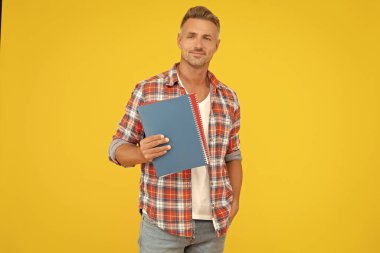 Eğitim için okul kitaplarını tutan mutlu öğretmen sarı arkaplan, kopyalama alanı.