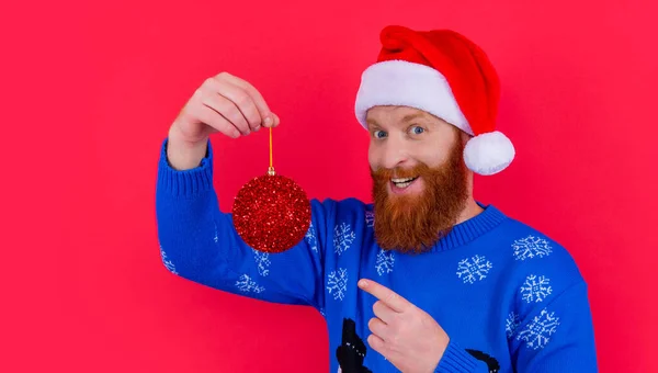 new year decoration. amazed bearded man hold new year decoration isolated on red background. man with new year decoration in studio.