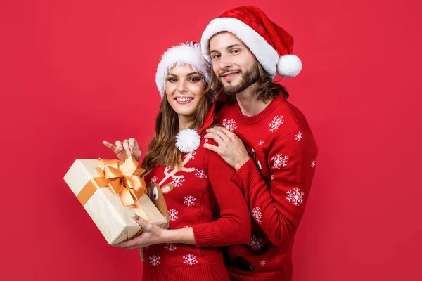 stock image Best time together. christmas time gift. happy new year couple in knitted sweater and santa hat. prepare for xmas party fun. happy holidays for young family. man and woman on red background. love.