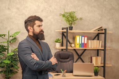 Başarılı, olgun, ceketli bir lider fotokopi alanı ve liderlikle ofiste duruyor..