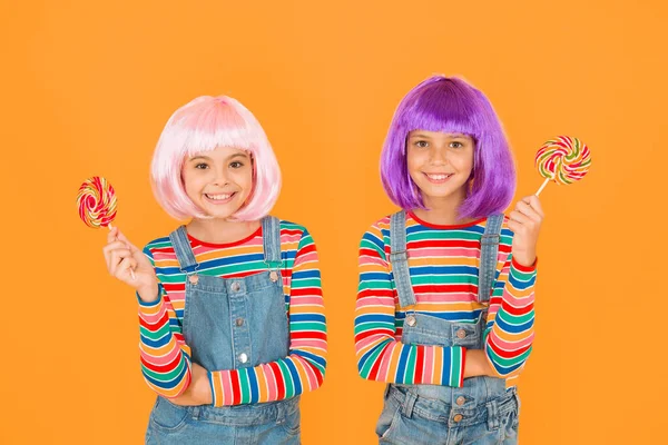 Anime cosplay party concept. Happy little girls. Anime fan. Kids with artificial hairstyles eating lollipops. Anime convention. Vibrant characters fantastical themes. Modern childhood. Childrens day.