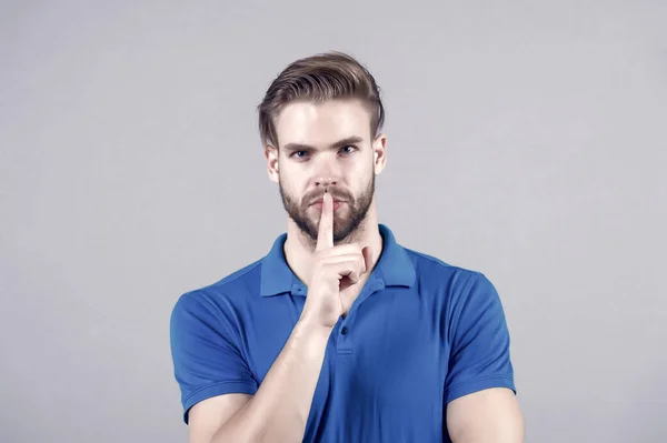 Bearded face with silence finger gesture. Bearded man with beard in blue tshirt, barbershop.