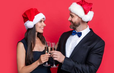 Noel partisini mutlu bir çiftle kutlayalım. Stüdyodaki çifte mutlu Noeller. Çift Noel 'i kutluyor. Tatili kutlayalım. Xmas çifti kırmızı arka planda izole edilmiş şampanyayla kutluyor.