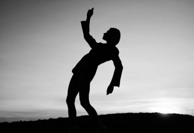 Gün batımında kadın silueti. Kadın gün doğumunda dans eder. Karanlık dansçı figürü. Akşamları dans ediyorum. Gölge ve gölge. Kadın silueti gökyüzü arka planında. Özgürlük duygusu.