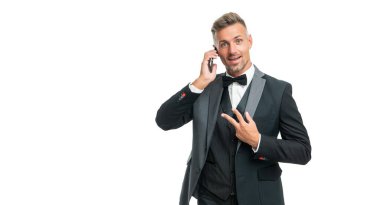 Smokinli şaşkın beyefendi telefonda konuşuyor. Beyaz arka planda izole bir şekilde barış jesti ile..