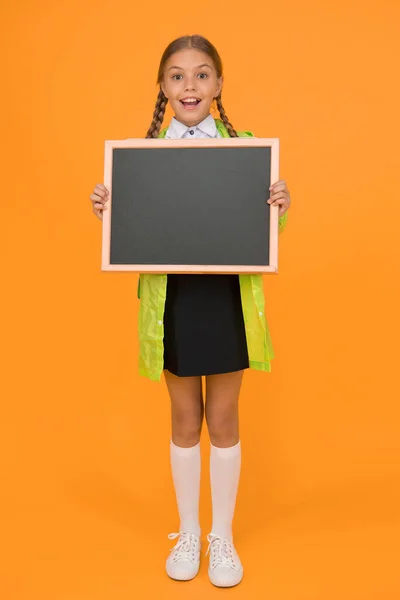 女子高生はレインコートを着て空白の黒板のコピースペースを保持します 快適な防水生地 防雨アクセサリー 防水服子供の女の子幸せなレインコートを着る 防水マント 天気予報 — ストック写真