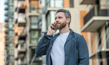 Yakışıklı bir adamın telefon konuşması. Yetişkin adam telefonda konuşuyor. Adam dışarıda telefonla konuşuyor. Erkekten bahset..