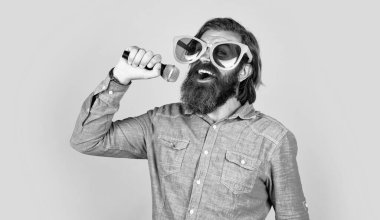 Talan edilmiş. Sakallı adam mikrofonda şarkı söylüyor. Vahşi Kafkas hipster etkinlik yöneticisi. Komik parti gözlükleri. Karaoke ve müzik. Mikrofonlu erkek hoparlör. Sesli. Mutlu gülümseyen olgun adam.