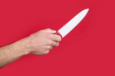 Keskin mutfak bıçağı kırmızı arka planda erkek elinde..