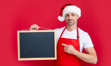Noel şapkalı ve önlüklü gülümseyen olgun bir adam yazı tahtasında fotokopi alanı ile işaret ediyor..