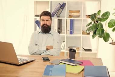 Kendine güvenen, kuşkucu iş adamı. Kollarını çapraz tutuyor. Ofis masasında oturuyor..