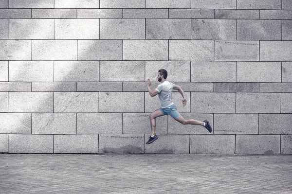 man running outdoor. Healthy male runner. hurry up. Full length portrait of fitness guy running. Achievement of success and excellence. Athlete running against concrete wall. Sport man starts to run.