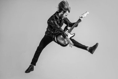 duygusal sakallı rock müzisyeni elektro gitar çalıyor deri ceketle ve zıplayarak, gitarist.