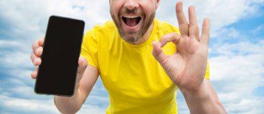 Akıllı telefon ekranı ile fotokopi alanı sunan adamın kırpılmış görüntüsü. Tamam.