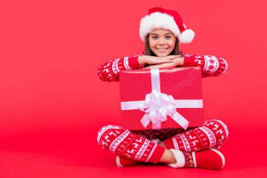 Yeni yıl. Olumlu Noel Baba kızı yeni yıl hediyesi olarak fotokopi odasıyla oturuyor. Genç kız, yeni yıl Noel Baba 'sını kırmızı arka planda izole bir şekilde bekletiyor..