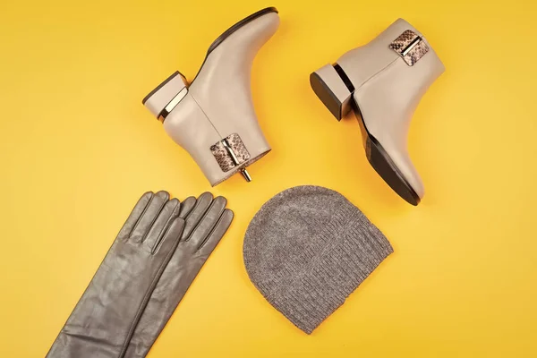 stylish leather boots gloves and hat on yellow background, fashion accessories.