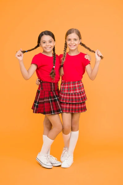 True friends. Cheerful friends. Happy together. School girls having fun together. Cute little girls smiling yellow background. Happy small girls wearing same outfits. Friends enjoying friendship.