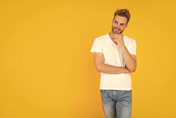 stock image man with bristle in white shirt. positive young man with beard on yellow background. hair and beard care. confident and handsome unshaven guy. male casual fashion. mens beauty.