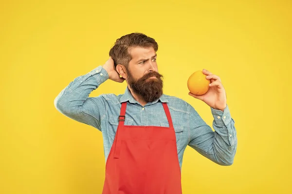 Μπερδεμένος Άνθρωπος Ποδιά Κοιτάζοντας Φρέσκα Φρούτα Πορτοκάλι Ξύνοντας Κεφάλι Κίτρινο — Φωτογραφία Αρχείου