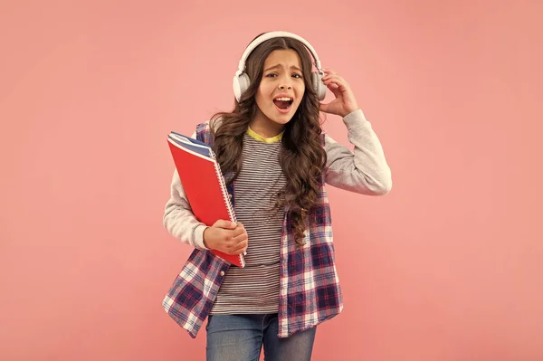 Verbaasd Tiener Meisje Met Werkboek Dragen Hoofdtelefoon Roze Achtergrond Onderwijs — Stockfoto