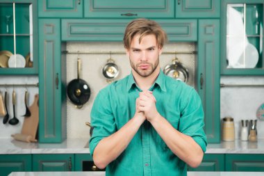 Mutfakta katlanmış parmak ile mavi gömlek standında ciddi bir yüz, sarı saçlı çocuk. Yiyecek hazırlama, kavram yemek mutfağı.