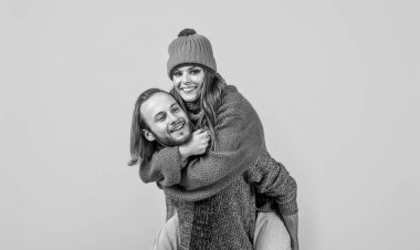 Mutlu, sevecen bir adam, kadını sırtında taşır, sevgi dolu bir çift sarı arka plan, şefkat.