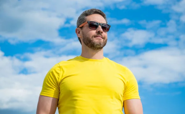 stock image stylish man in yellow shirt and sunglasses outdoor on sky background.