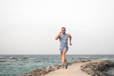 Hızlı koş ya da sonuncu ol. Sahilde koşan adam. Koşucu eğitim açık havada. Fit yaz aylarında erkek spor fitness egzersiz. Koşu sporu ve hobi. Günlük egzersiz büyük sonuç. Erkek profesyonel fitness antrenörü.