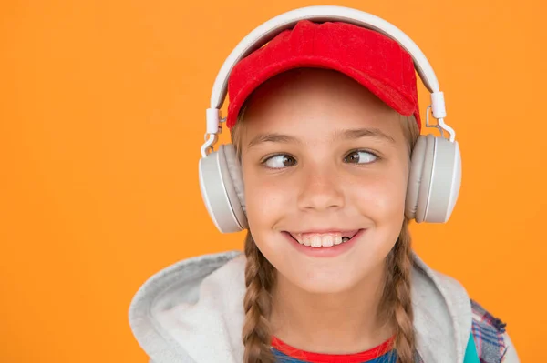 Music with emotions. Squint-eyed kid on yellow background. Funny child listen to music in stereo headphones. Small child enjoy music playing in earphones. Non-stop music for more fun.