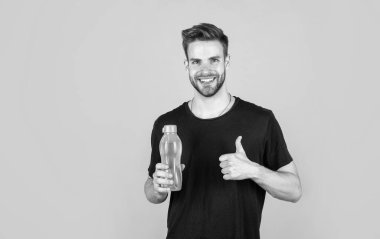 Başparmağını kaldır. Adam spordan sonra rahatlar. Susadım. Suyu dengede tut. Susuzluk. Yakışıklı genç adam su içiyor. Sıradan yaz modası. Erkek güzellik ve moda. Adam plastik şişe tutuyor..