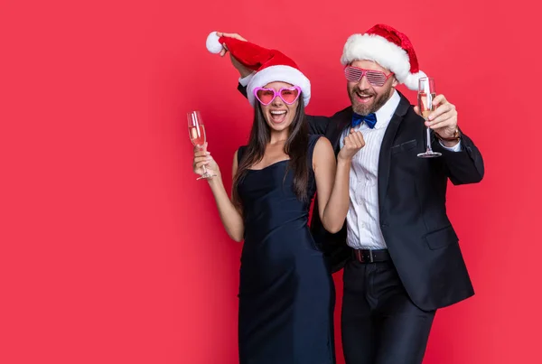 couple celebrate christmas and have fun. lets celebrate holiday. christmas couple celebrate with champagne isolated on red. celebrate christmas party with couple. merry christmas to couple in studio.