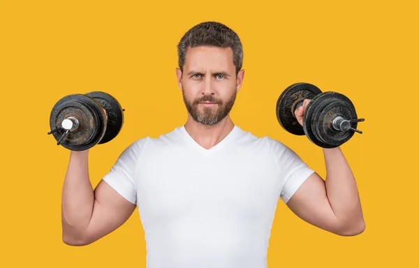 スタジオでバーベルと筋肉フィットネスの男のトレーニング 筋肉フィットネスの男はシャツにベルを持ってる バーベルと筋肉フィットネスの男 黄色で隔離されたバーベルと筋肉フィットネスの男のトレーニング — ストック写真