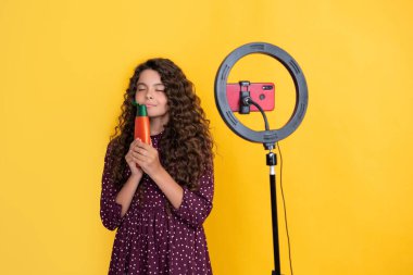 Uzun kıvırcık saçlı çocuk blog kokusu şampuanı için video yapıyor.