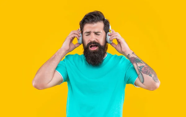 留着胡子的家伙喜欢用黄色背景的耳机听音乐 用耳机听音乐的家伙 听音乐概念 工作室拍摄的家伙与耳机 很酷的家伙听音乐 — 图库照片