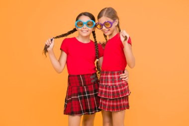 Yaz moda trendi. Yaz eğlencesi. Yaz aksesuarı. Kızlar sevimli kız benzer kıyafetler yaz sezonu için renkli güneş gözlüğü giymek. Çocuklar moda arkadaşlar sarı arka plan üzerinde güneş gözlüğü poz.